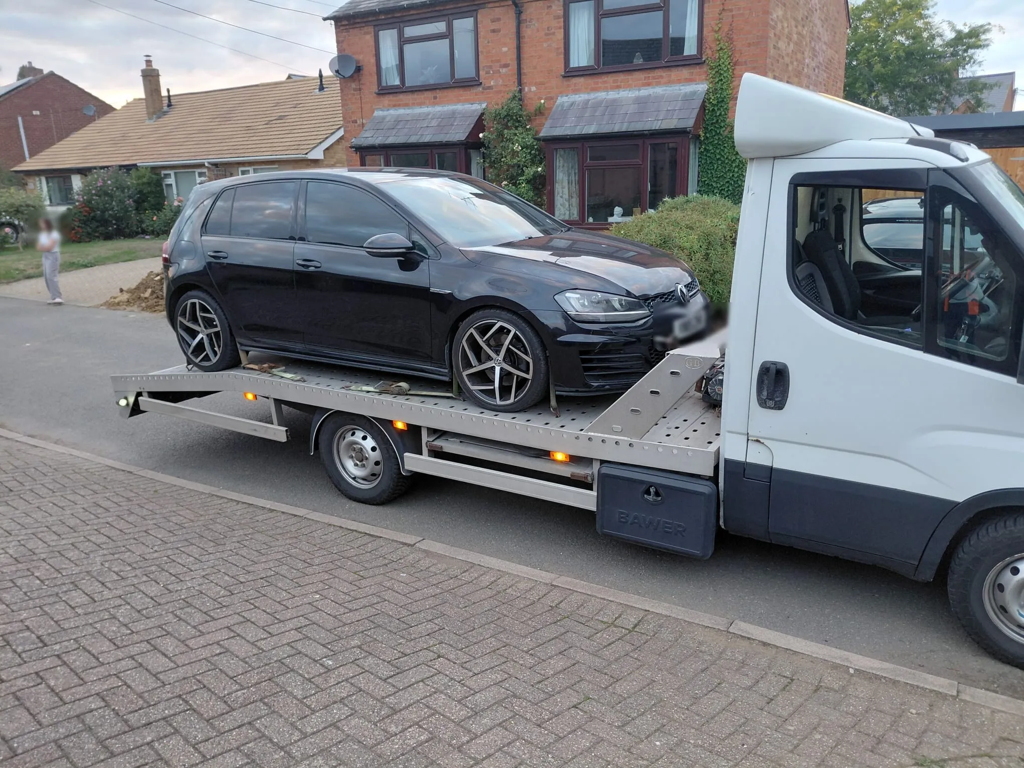 Black VW Golf GTD loaded on the VP Autos transporter outside a house