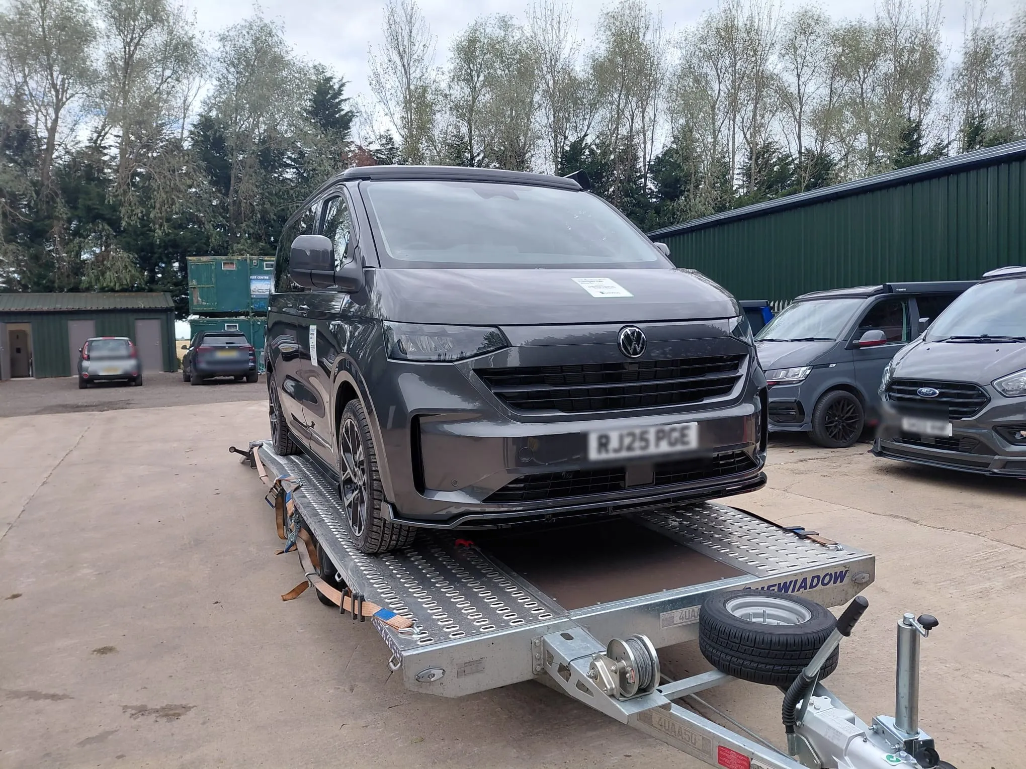 New grey VW Transporter secured on the trailer at a depot