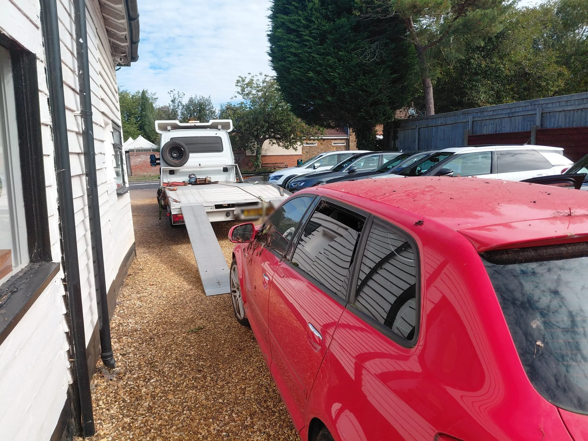 Recovery transporter with ramps down collecting a car at a yard